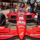 Three teenage girls pose with an open-wheel car during a Della Penna Next Gen Foundation karting event.